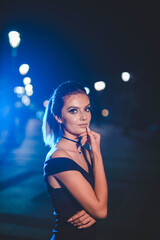 Poster - Attractive young female in an elegant black dress posing in the street at night