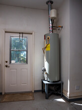 Natural Gas Hot Water Heater Tank With Copper Pipe Plumbing In Residential Garage.