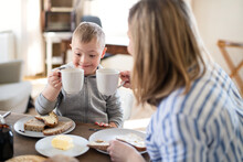 Single Mother Having Breakfast With Down Syndrome Child At Home.