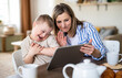 © Halfpoint - Single mother with down syndrome child at home, video call on tablet.