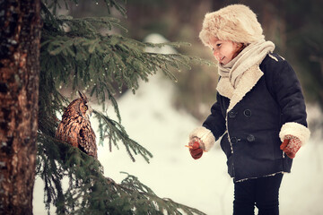 Little girl is meeting an owl in Russian forest in winter. Image with selective focus and toning