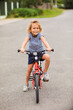 © oksix - The little girl rides a bike in the city