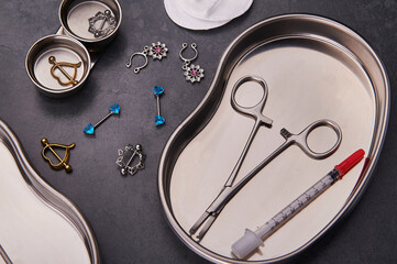 Wall Mural - Piercing earrings, stainless steel clips for disinfection on a black background