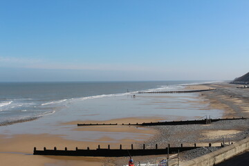 Wall Mural - Cromer, Nortfolk, coast from the top, people walking on the bech winter, seaside gentle waves crashing on the shore, north sea, seascape, northern Europe, beautiful Englad 