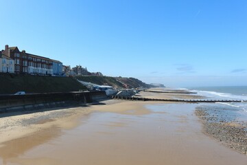 cromer, nortfolk, man walking on the beach, winter, seaside gentle waves crashing on the shore, nort