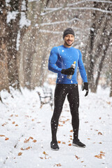 Sticker - Fit man in running clothes holding a drink bottle on a snowy day outdoors