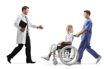 Wall Mural - Full length profile shot of a doctor greeting a young woman patient in a wheelchair and a male nurse