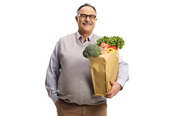 Canvas Print - Smiling mature man holding a grocery bag with healthy food