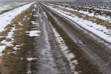 A Dirt Dirt Road Running Through Farmland In Late Winter
