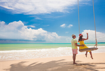 Wall Mural - Couple in love on a swing by the sea. Couple in love on an island off the coast. Honeymoon.