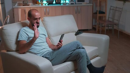 Poster - Focused adult talking with friends about social media connection using modern smartphone while sitting on couch. Tired man working late at night in kitchen using modern technology wireless
