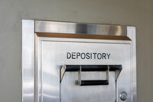 Depository Sign On An Exterior Secured Bank Drop Box Attached To The Wall Of A Bank Building.