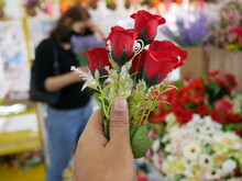 Closeup Of Hand Holding Red Fake Rose.
