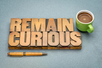 Wall Mural - remain curious word abstract in vintage letterpress wood type with a cup of coffee, open and active 