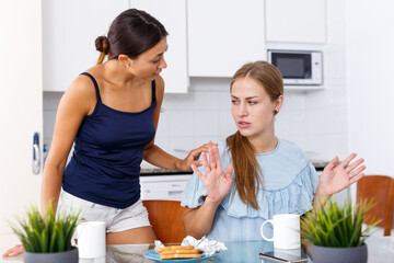 Emotional quarrel between two young women friends in kitchen interior