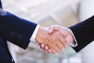 A close-up picture of a businessman shaking hands on a business cooperation agreement in the heart of the city. Concept of Cooperation business and success