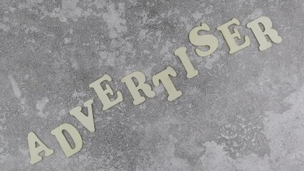 Fototapete - Advertiser concept with decorative alphabet letters in an undulating line on a textured grey background viewed as a flat lay with copyspace. Rotation
