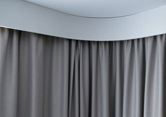 Angular cornice with drapes and white curtain or tulle. Interior details close up. White wall, ceiling, cornice niche, curtains on the window. Corner white plastic hidden curtain rod.