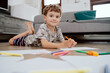 © ABCreative - Portrait of school-age boy lies on the living room floor and paints pictures on white sheets of paper with colored markers. The boy is spending his afternoon free time at home.