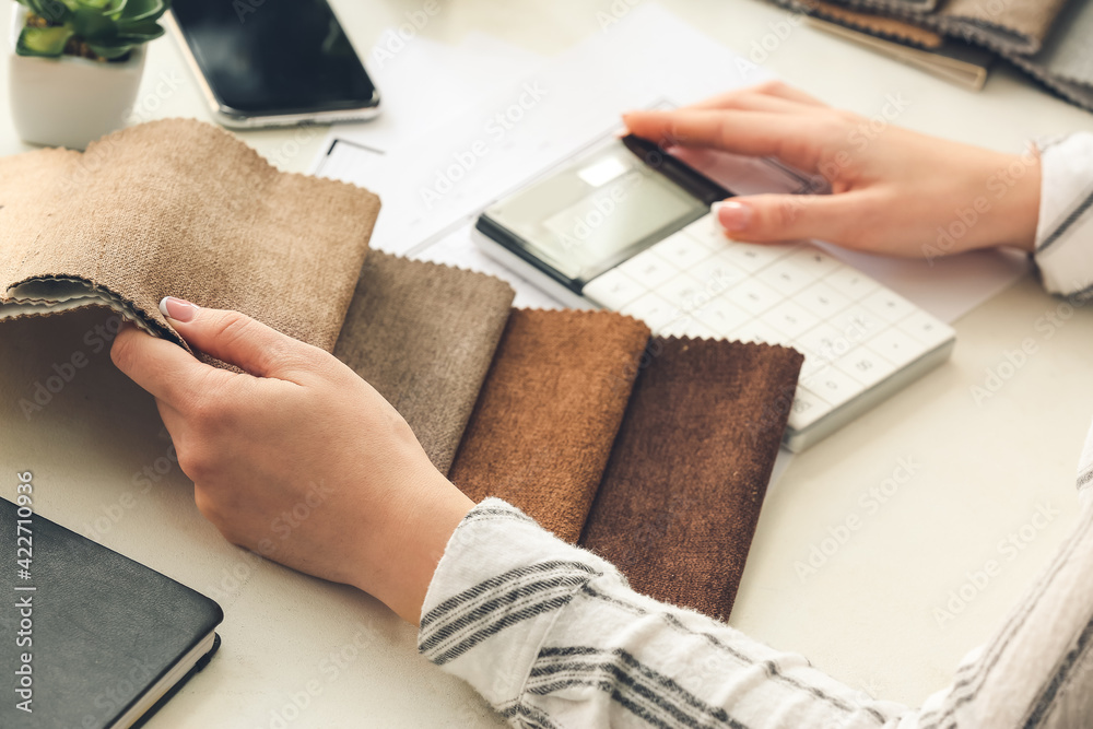 Female interior designer with calculator and fabric samples in office