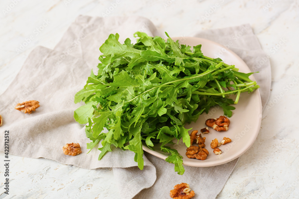 Plate with arugula on light background