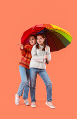 Canvas Print - Portrait of cute twin girls with umbrella on color background