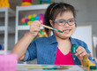 © Bangkok Click Studio - Young Asian down syndrome little girl sitting at desk with colors and painting with concentrated and calm. painting. Concept for education for disabled kid