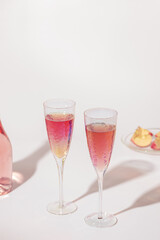 Wall Mural - Bottle of rose champagne sparkling wine and beatiful bright glasses with sunlight on light table