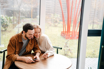 Sticker - Happy young couple talking while sitting in cafe indoors