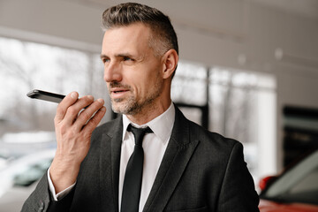 Sticker - Mature white man talking on speakerphone while choosing car in showroom