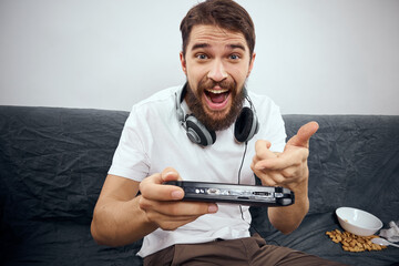 Wall Mural - cheerful man sitting on the couch playing entertainment technology