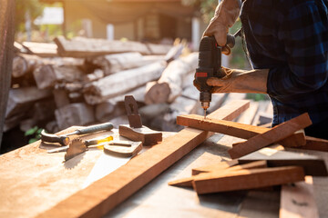 hand of Carpenter drills wood a hole with an electrical drill.