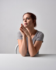 Poster - 3/4 close up portrait of red haired girl wearing striped shirt. Leaning on table pose with studio background.