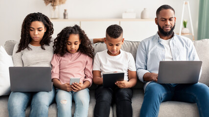 Wall Mural - Focused african american family holding and using gadgets