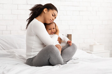 Wall Mural - African Mother Hushing Crying Newborn Baby To Sleep In Bedroom