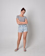 © faestock - full length  portrait of girl wearing shirt and denim shorts. Standing pose isolated on grey studio background.