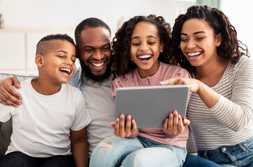 Wall Mural - Happy African American family using tablet sitting on the couch