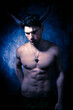 Sexy shirtless male devil with horns and muscular body showing pecs and abs