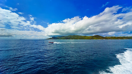 seascape, dark blue waters of the sea, blue sky with white clouds. a boat glides through the water a