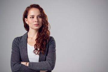 Wall Mural - Studio Portrait Of Serious Young Businesswoman With Folded Arms Against Plain Background