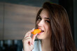Close up woman eating nibbling carrot and smiling in the kitchen interior.. Health diet food. nibble on a carrot