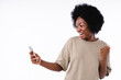 Excited as a winner young afro girl using smart phone isolated over white background