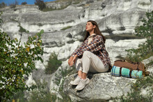 Young Woman Relaxing On Rock While Hiking Outdoors