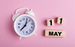 © Елена Дигилевич - On a pink background, a white alarm clock and wooden cubes with the date of MAY 11