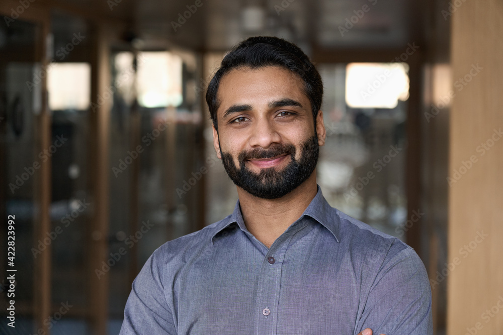 Portrait of young happy indian business man executive looking at camera. Eastern male professional teacher, smiling ethnic bearded entrepreneur or manager posing in office, close up face headshot. - obrazy, fototapety, plakaty 