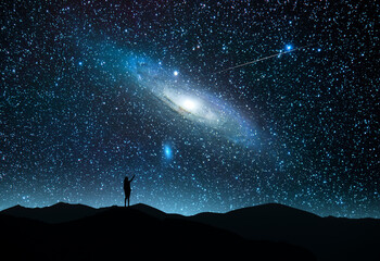 Wall Mural - the girl silhouett stands on the hill and looking at the bright starry sky with andromeda galaxy and