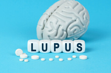 Wall Mural - Cubes lie on the table among the pills and imitation of the brain. The text on the dice - LUPUS