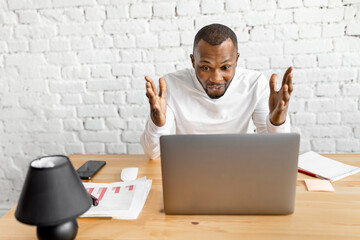 Excited african american business man is looking at the laptop screen, smiling, reading good news. Overjoyed male freelancer or student well done with work project or pass the exams, success concept