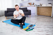 © DSMT - The man goes in for sports at home. Athlete drinks water while sitting on the floor at home, healthy lifestyle