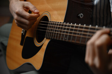 Man playing acoustic guitar, cover for online courses, learning at home.